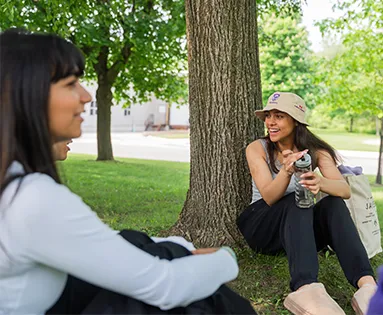 Two students sitting around a tree