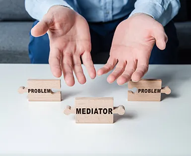 Two hands displaying puzzle pieces showing problems and mediator